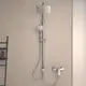 Duschsystem von Ideal Standard mit Kopf- und Handbrause, montiert an einer Wand. Chromoberfläche, flexibles Schlauchsystem und integrierte Armatur sichtbar.